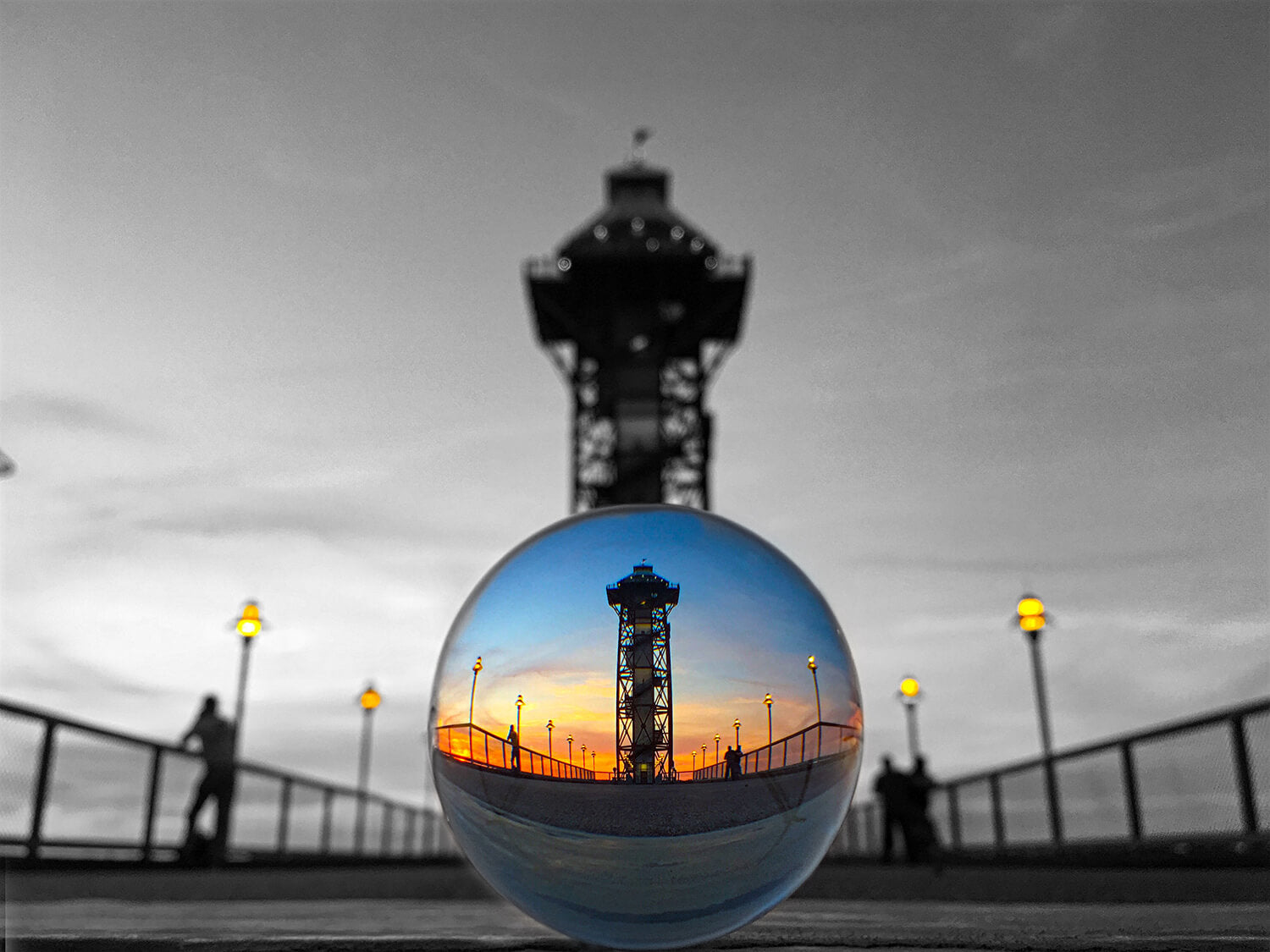 Greyscale photograph of a crystal sphere featuring a colorful reflection of the bicentennial tower 