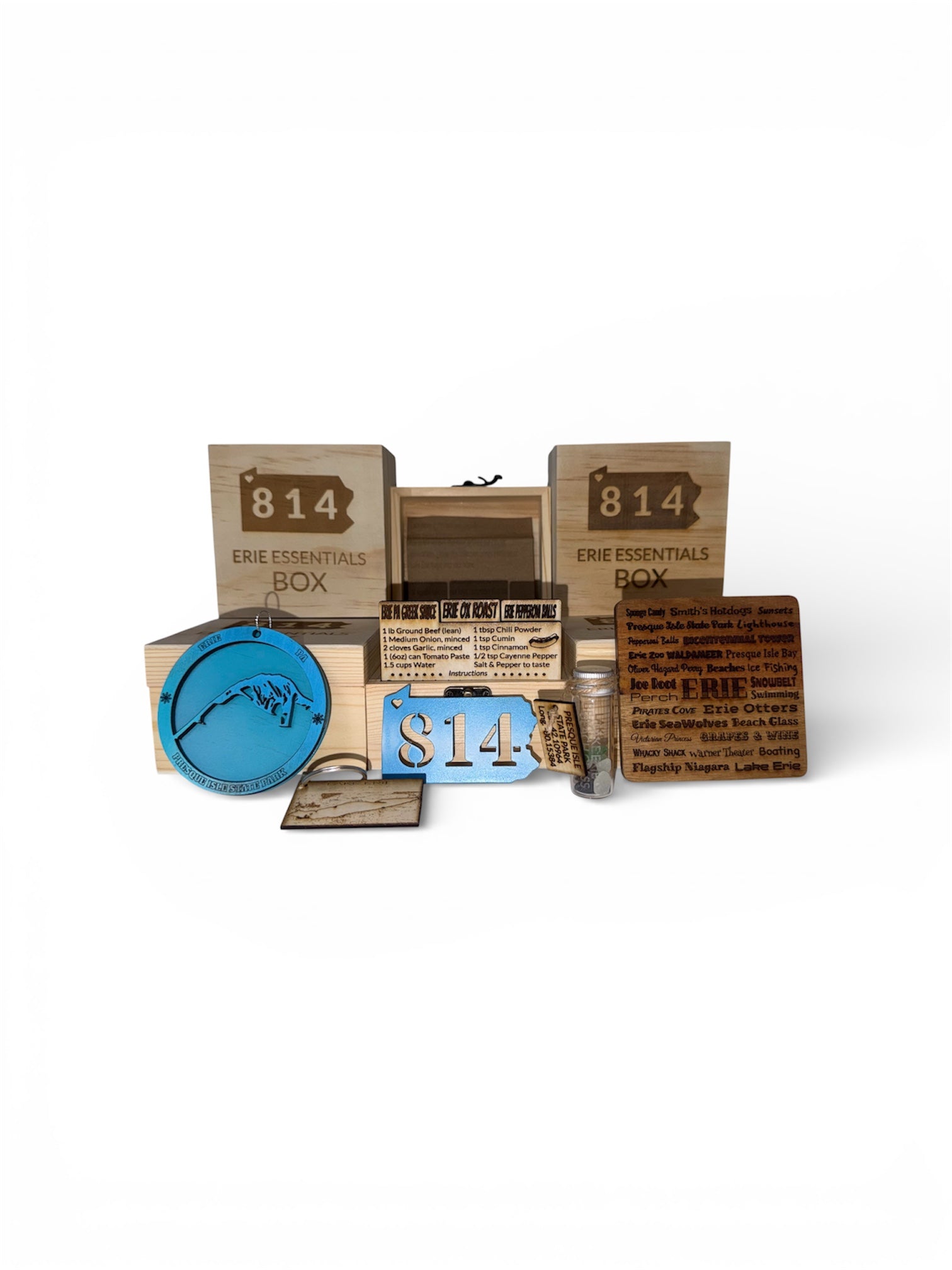 A flat-lay showcase of the complete Erie 814 collection, featuring a wooden keepsake box, engraved recipe cards for local dishes, authentic Lake Erie beach glass, and various Presque Isle themed ornaments and keychains.