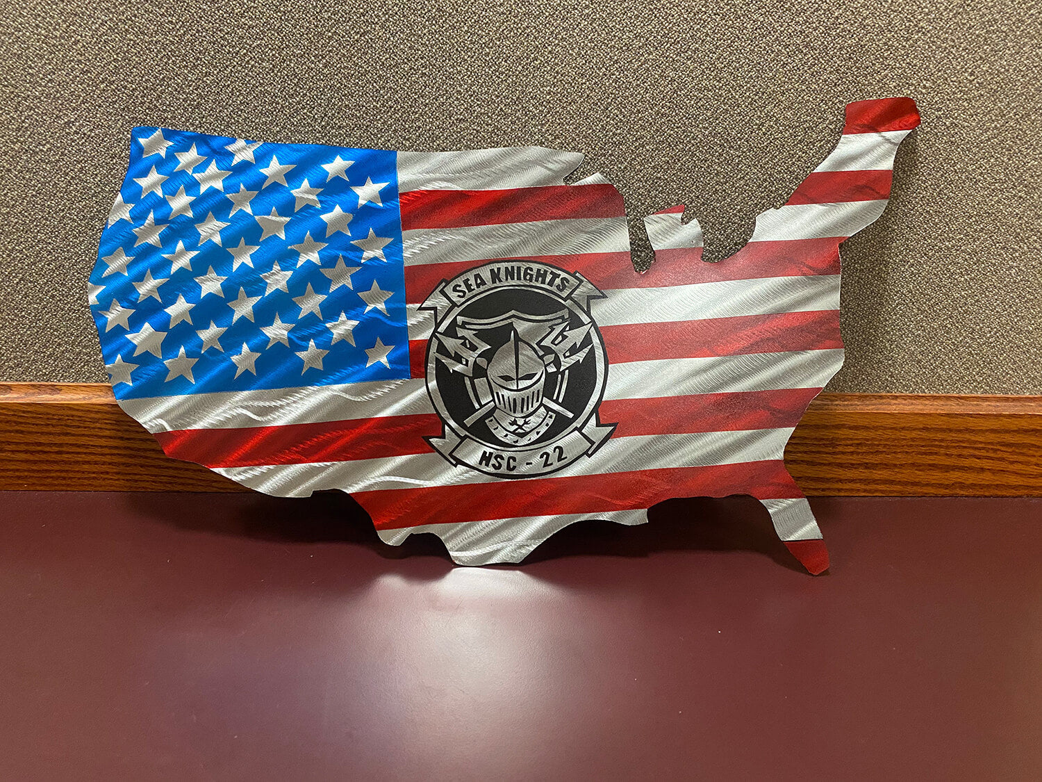 Metal artwork of a the United States colored liked an American flag leaning against a wall. The Sea Knights logo is in the middle.