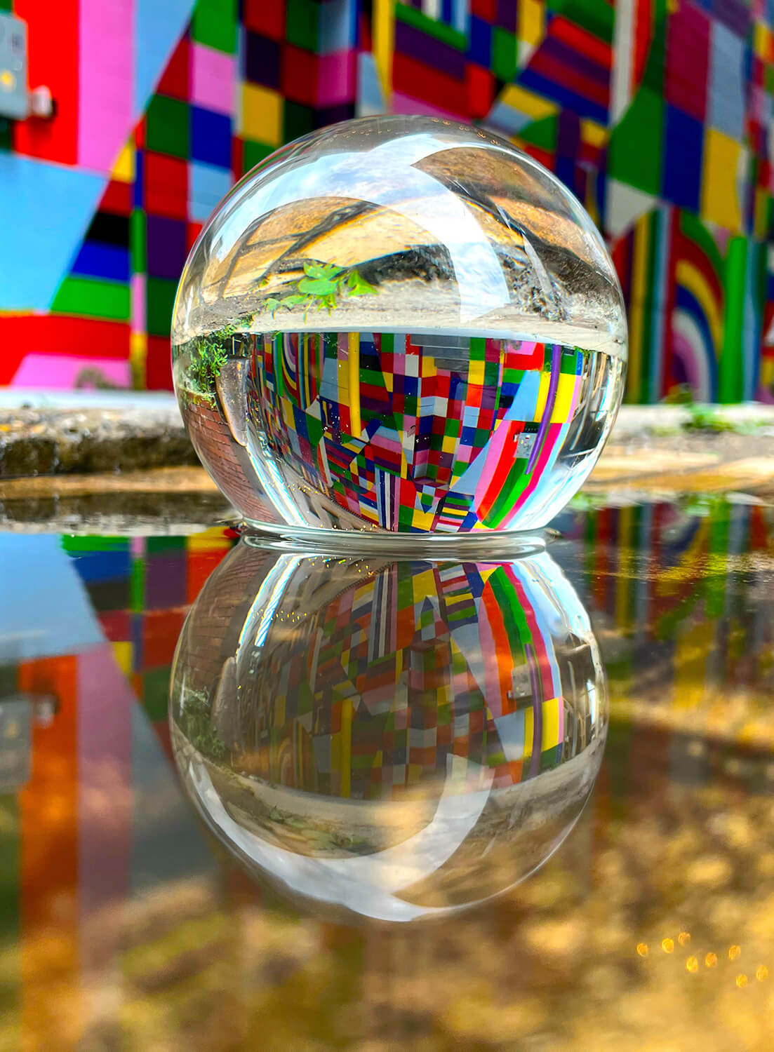 A photograph of a crystal ball reflecting a bright multicolored piece of art