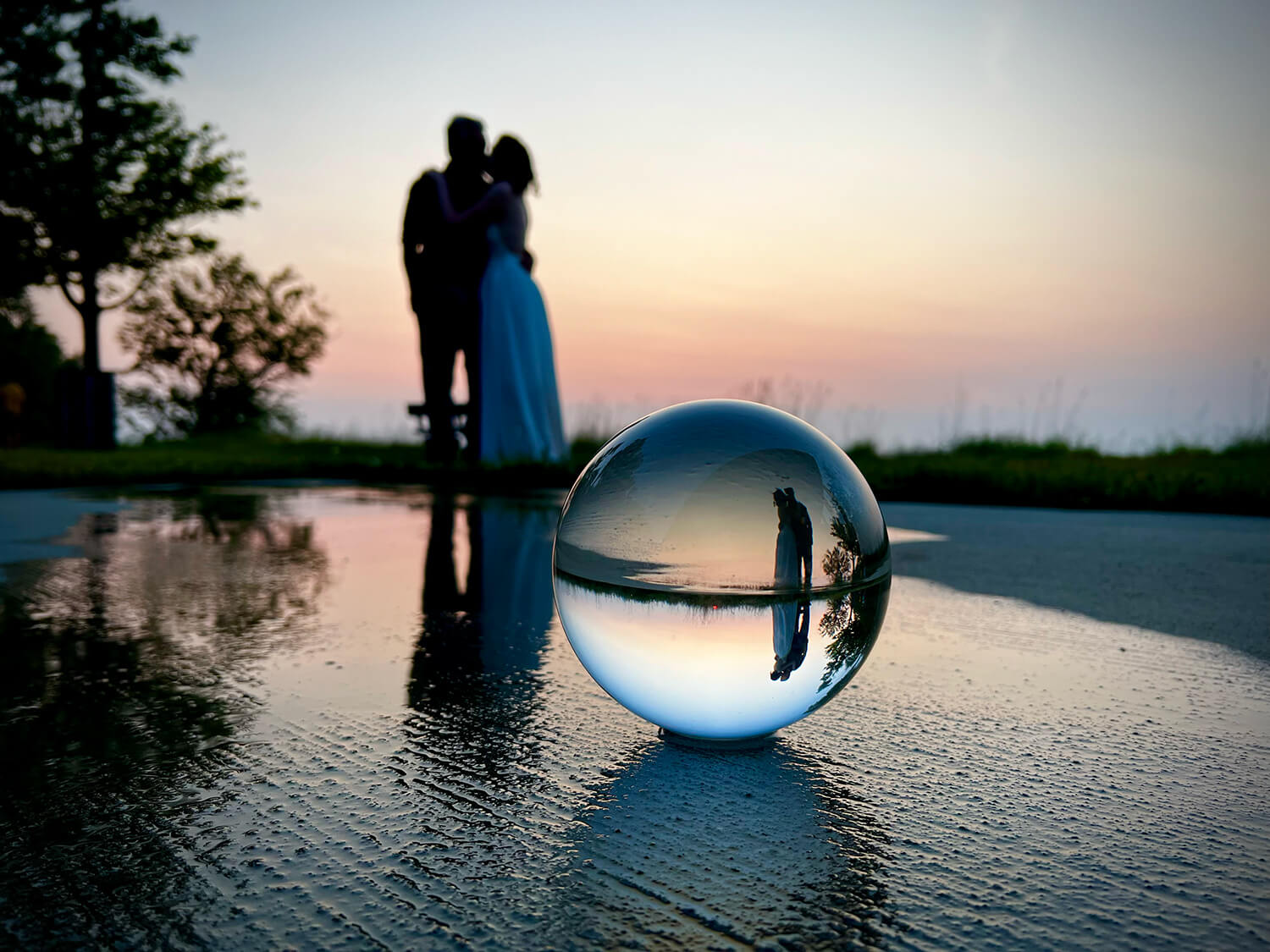 Photograph of a couple embracing featuring a crystal ball reflecting their embrace
